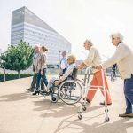 Group of elderly people in wheelchairs and walkers