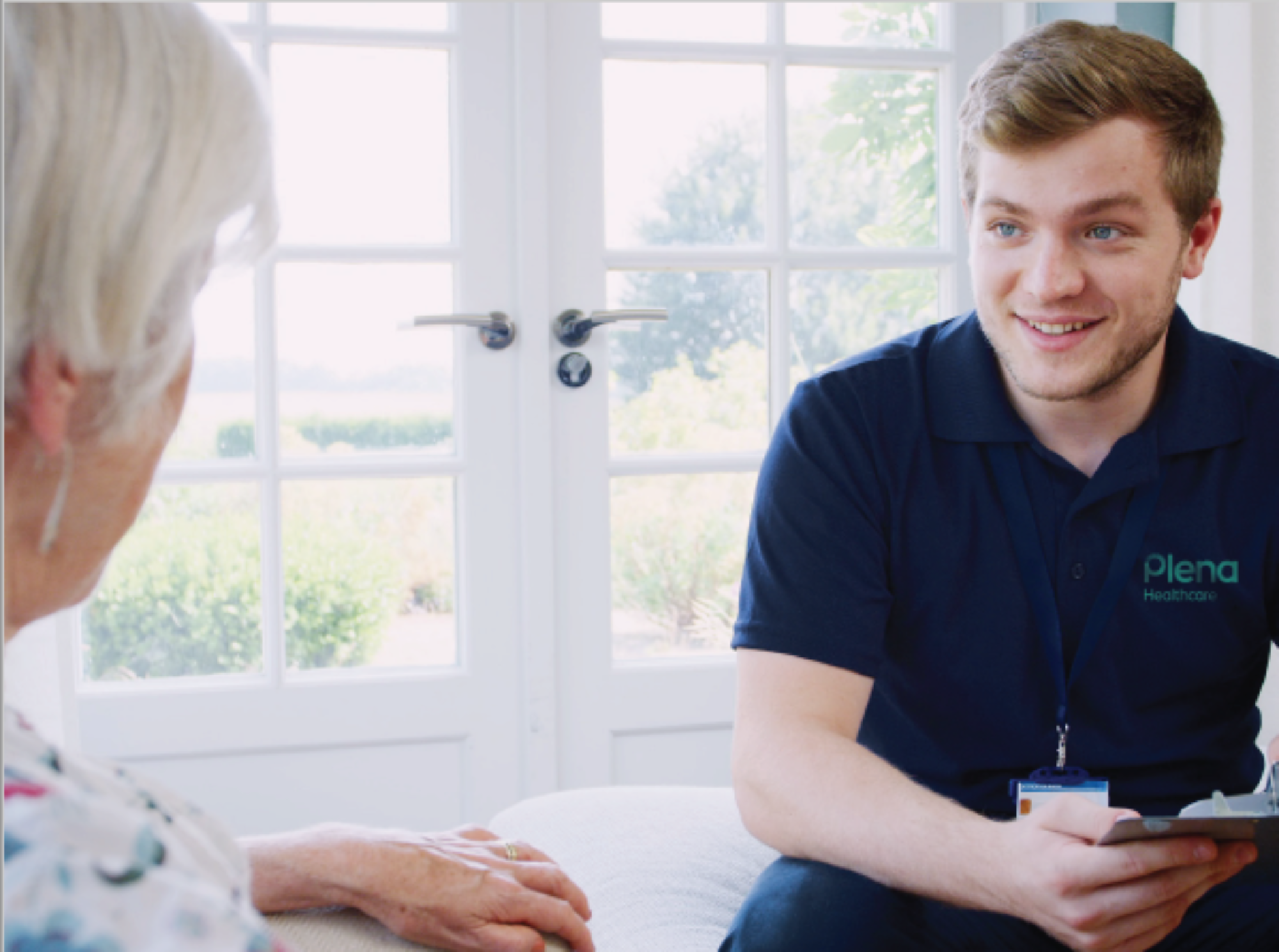 plena staff member sitting facing an older person