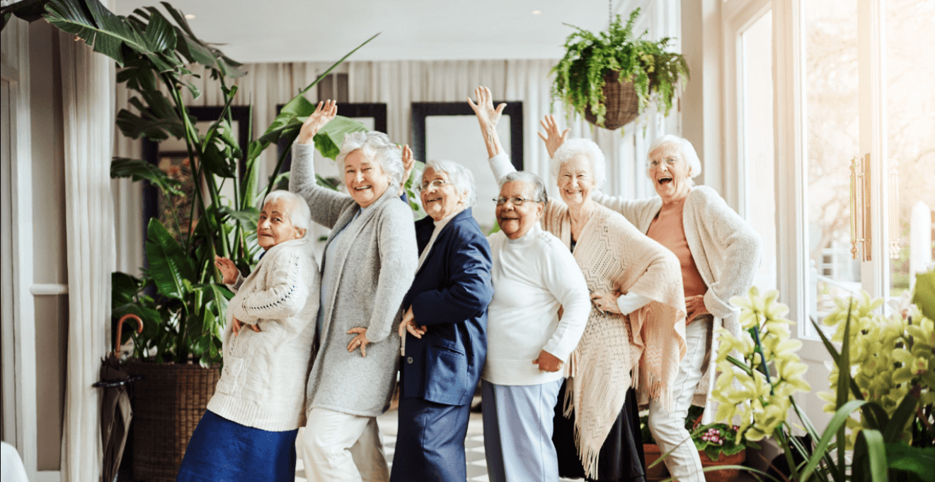 Group of six elderly women smiling and waving