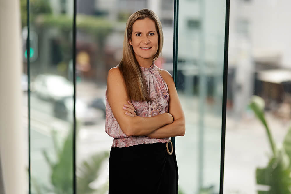Image of COO, Tenille Douglas, smiling at the camera with her arms crossed