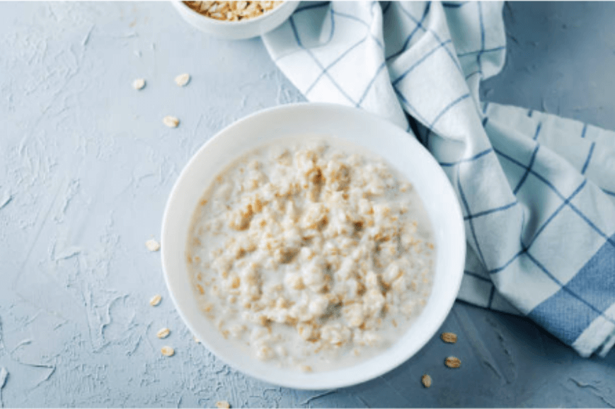 A bowl of oats on a blue table with a blue and white tea towel next to it.