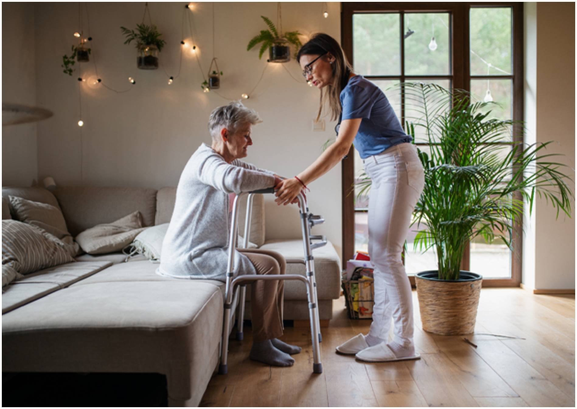 A Physiotherapist assisting an older woman sitting down, both are holding on to a walker