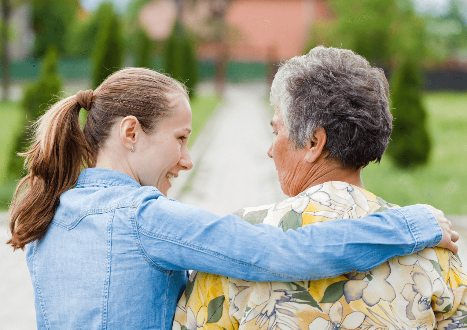 A younger woman puts her arm around an older woman.