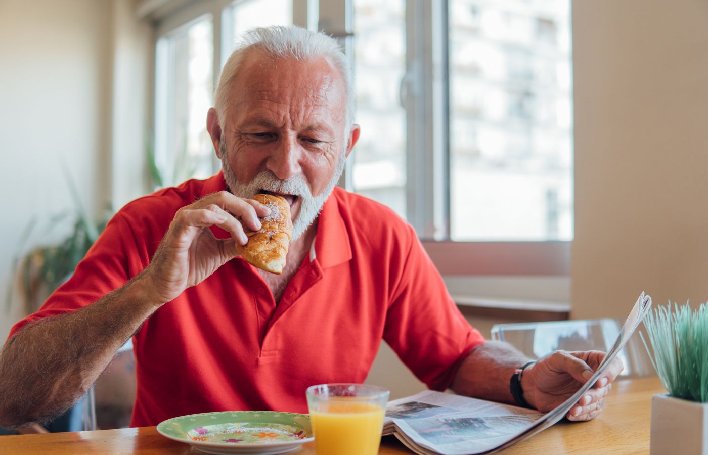 Older man sitting at a table eating and drinking